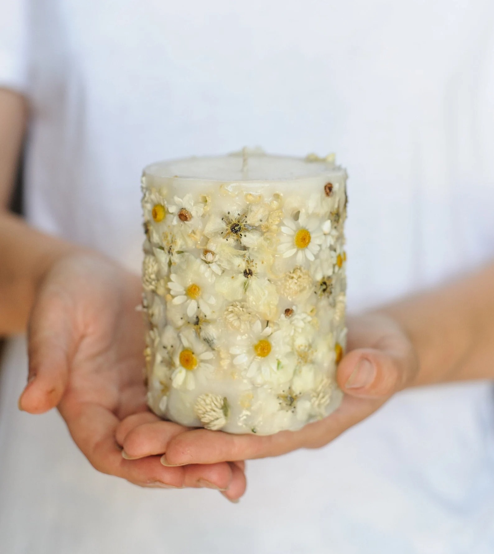Lumânare pilon cu margarete și ierburi uscate în ceară